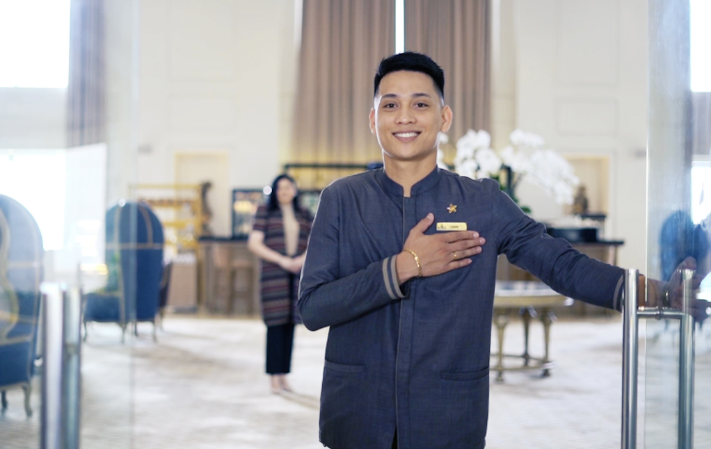 Hotelier in a blue uniform greeting guests at a Megaworld Hotel & Resort lobby, Philippines