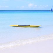 Yellow paddle board in the water of White Beach Boracay Island with a local paraw boat in the background. Article Boracay Ranked 10th Among Worlds Best islands, by MY RANGGO Philippine Hospitality Magazine